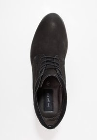 Chaussure en daim noir avec bout rond, lacets, surpiqûres contrastantes et semelle intérieure de marque. La semelle est lisse avec une légère courbe. Taille 42.