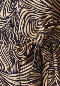 Materiał w kolorze granatowym i beżowym z wzorem falistych linii, guzikami oraz wiązaniem w talii, o gładkiej fakturze i uporządkowanym kroju.