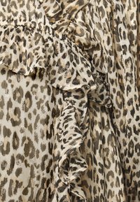 Tecido com padrão de leopardo e detalhes em babados. Textura suave e leve em tons de bege e marrom, com acabamentos metálicos ao longo do padrão.