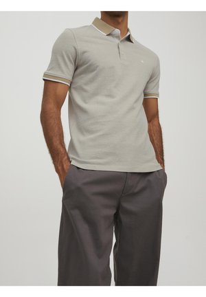 Light gray polo shirt with a contrasting tan collar and cuff stripes, made of a soft fabric, featuring a three-button placket and logo.
