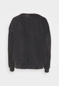 Sudadera negra de cuello redondo con una textura ligeramente desgastada, hombros caídos y puños acanalados. Diseño simple y sin adornos; sin logotipos visibles.