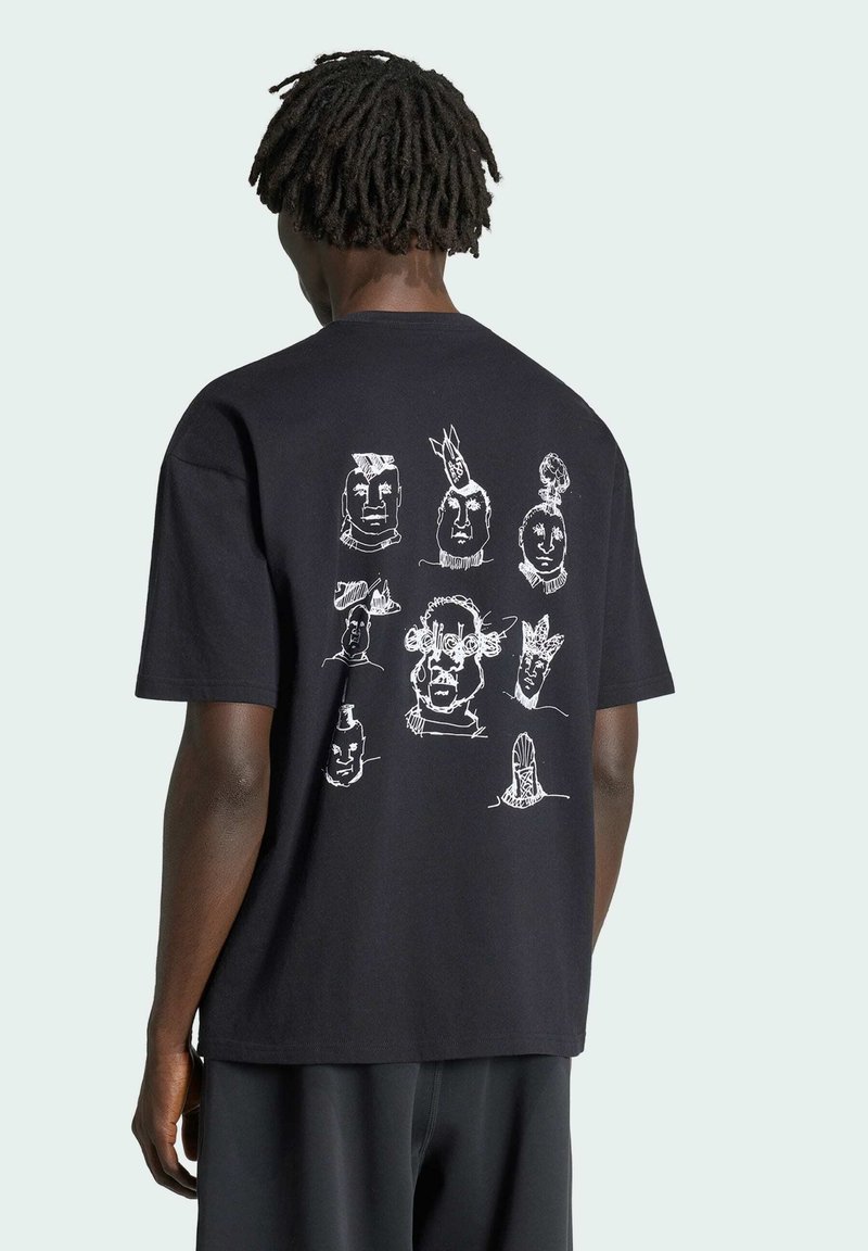 Person mit dunkler Haut und kurzen Dreadlocks trägt ein schwarzes T-Shirt mit neun weißen abstrakten Gesichtern, die in einem Raster auf dem Rücken angeordnet sind.