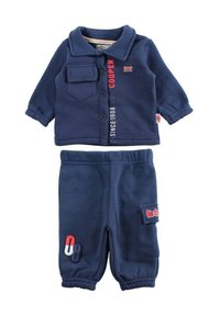 Ensemble en polaire bleu marine comprenant un haut boutonné à manches longues avec une poche poitrine et un logo. Pantalon en polaire assorti avec poche latérale.