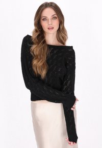 Schwarzer gestrickter Pullover mit lockerer Passform, weitem Ausschnitt und langen Ärmeln. Verfügt über ein texturiertes, spitzenähnliches Muster. Glatte Oberfläche, cropped Länge.
