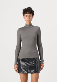 Pilkas raibos turtleneck stiliaus ilgomis rankovėmis viršus, derinamas su juodu blizgučių mini sijonu. Viršus turi prigludusią siluetą ir lygų paviršių.