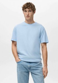 Světlomodré tričko s krátkým rukávem z měkké látky, s kulatým výstřihem a pohodlným střihem, kombinované se světlomodrými džínami.