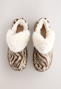 Chaussons en fausse fourrure à imprimé zèbre, avec un revers de couleur crème douce et des coutures soulignées. Bout rond et semelle plate.