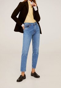 Vaaleansiniset farkut, joissa on korkea vyötärö ja suora kuvio, varustettuna etutaskuilla ja klassisella viiden taskun suunnittelulla, yhdistettynä mustaan bleiseriin.