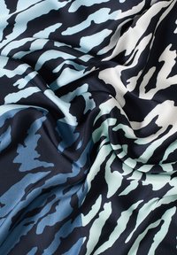 Tessuto di seta con un motivo a onde nei toni del blu navy, azzurro e bianco. Texture morbida con una caduta fluida e sezioni di colore a contrasto.