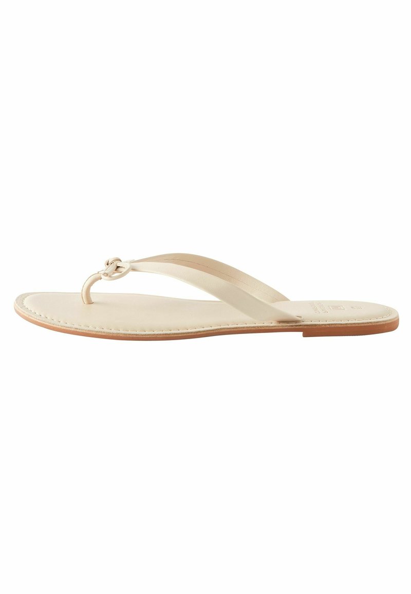 Beige flip-flop sandaalit, joissa on kaksi ohutta remmiä, keskuslenkki ja litteä nahkapohja vaaleanruskealla reunalla.