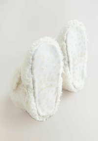 Vit, fluffig tofflor med en mjuk textur, prydda med ett prickigt mönster på sulan och präglad text "little & loved".