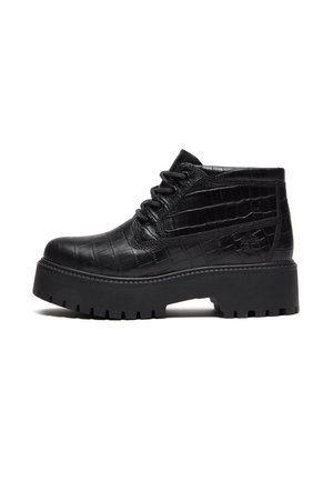 Bottine noire montant à la cheville avec semelle épaisse crantée, fermeture à lacets sur le devant et dessus en cuir à motif crocodile texturé.