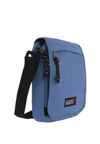 Bolso mensajero azul con una tela texturizada, correa negra ajustable y cierre con cremallera. Presenta un logotipo de la marca en un parche rectangular.