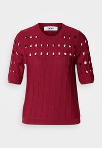 Punainen neulepusero, jossa on lyhyet hihat, vaakasuuntainen ribbaus sekä ympyräleikkaukset vartalon ja hartioiden alueilla. Klassinen pyöreä pääntie.