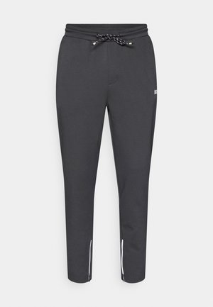 Μαύρο tapered joggers με ελαστική μέση που ρυθμίζεται με κορδόνι, πλαϊνές τσέπες με φερμουάρ και λευκές λεπτομέρειες στον αστράγαλο. Φτιαγμένα από απαλό, ελαστικό ύφασμ�α.