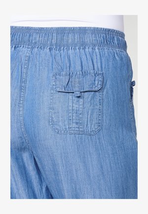 Világoskék, farmer stílusú nadrág, elasztikus derékkal és egy hátsó zsebbel, amelyen fedél található. Az anyag sima, enyhén texturált felületű.