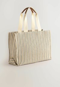 Rektangulär tote-väska i beige med svarta vertikala ränder. Har ett hållbart tyg, två tyghandtag och ett rymligt inre utan synlig hårdvara.