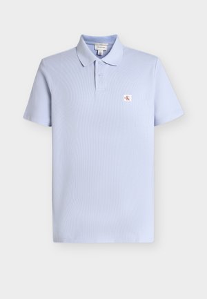 Polo bleu clair à manches courtes avec deux boutons, col et petit logo CK rouge et blanc sur la poitrine gauche.