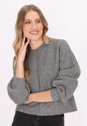 Maglione grigio corto con texture a coste, scollo rotondo e maniche voluminose, abbinato a jeans scuri.