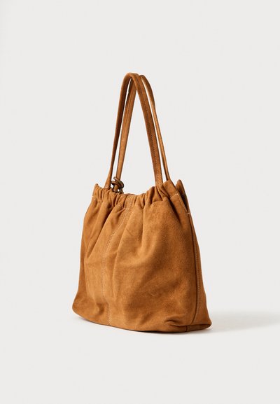 Braune Wildleder-Shopper-Tasche mit weicher Textur, gerafftem oberen Teil und zwei langen Griffen. Verfügt über dezente Nahtdetails entlang der Nähte.
