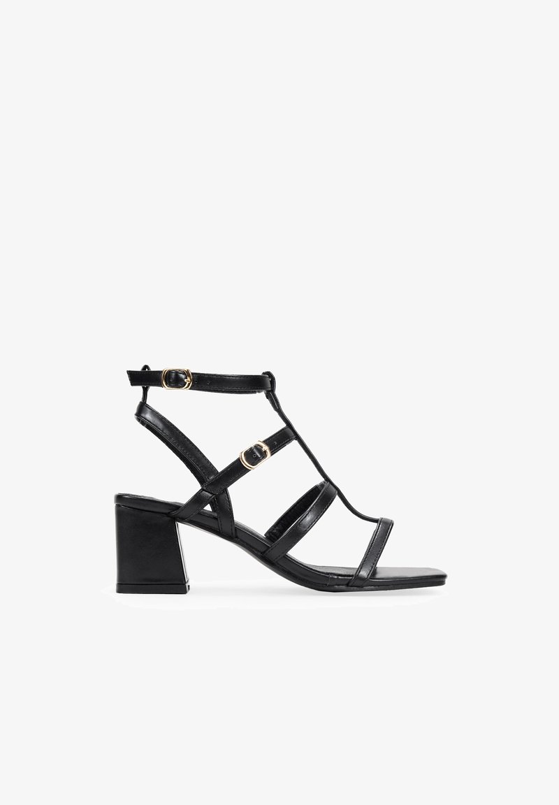 Sandalias negras de tacón con puntera abierta, que cuentan con tiras delgadas, acentos de metal dorado y un diseño de tacón cuadrado.