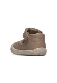 Tanfärgad lädersko för småbarn med en sluten design, en justerbar kardborreband och en strukturerad gummisula. Sidologotyp är synlig.