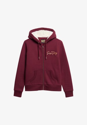 Bordeaux kleurige ritsvest met een zachte witte fleece voering, voorzakken, trekkoord capuchon en een gouden "Superdry NYC" logo op de borst.