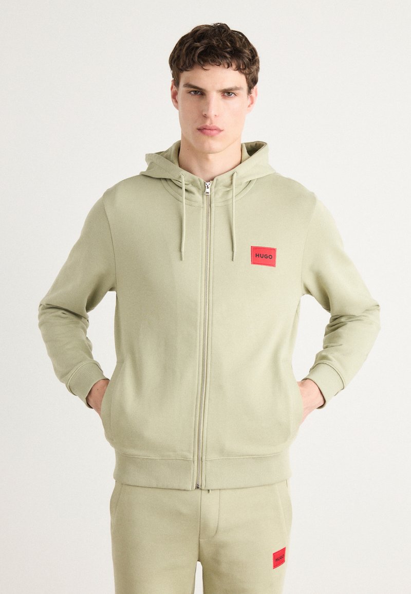 Felpa verde chiaro con zip realizzata in morbido cotone, caratterizzata da un logo rosso in patch sul davanti e cappuccio regolabile con cordino, con polsini e orlo a coste.