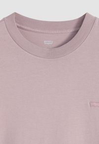 Sweatshirt en coton rose clair à col rond avec des poignets et un col côtelés. Présente un petit logo brodé sur la poitrine. Texture douce.