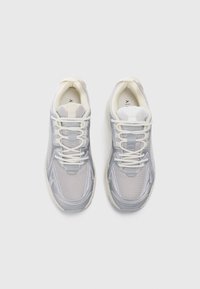 Grå mesh og syntetisk overdel sneakers med hvite snørebånd, avrundet tå og vadert krage. Har logo detaljer på sidene og tungen.