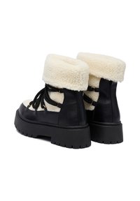 Czarne platformy z grubym beżowym futrem podwijanym na górze oraz czarnymi sznurówkami, zaprojektowane na zimne dni.