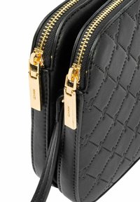 Czarna pikowana skórzana torebka z dwoma złotymi zamkami błyskawicznymi i pasującymi, złotymi uchwytami zamków, ukazująca szczegółowe przeszycia i fakturę.