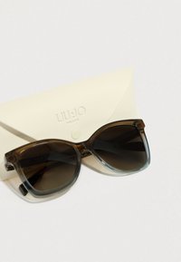 Teknőcmintás napszemüveg gradiens lencsékkel, széles, négyzet alakú és fényes felületű, krémszínű, texturált tokon logóval elhelyezve.