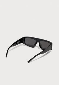 Schwarze Sonnenbrille mit einem eleganten, rechteckigen Design. Ausgestattet mit dunklen Gläsern, glatten Kunststoffrahmen und geraden, schmalen Bügeln.