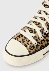 Αθλητικά παπούτσια με σχέδιο λεοπάρ, σε καφέ υφή, λευκή κορδόνι και κρεμ καπάκι στο μπροστινό μέρος. Μαύρη λεπτομέρ�εια κατά μήκος των άκρων της σόλας.