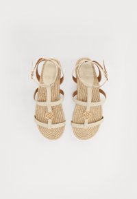 Beige strappy sandaalit, joissa on kudottu köysipohja, kultainen pyöreä yksityiskohta ja säädettävä nilkkaremmi. Silkkisen sileä päälliskangas.