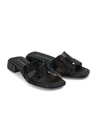 Sandalias negras tipo slide con dobles correas cruzadas adornadas con piedras de strass negras texturizadas y un pequeño tacón cuadrado. Suela plana, diseño moderno.