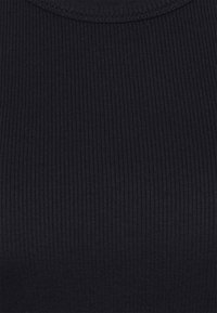 Tissu noir côtelé avec une coupe ajustée, présentant un col arrondi et une texture créée par des rayures verticales.