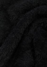 Gros plan sur un tissu doux, noir et duveteux avec une surface moelleuse texturée et des fibres visibles.