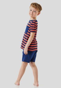 Red and navy striped t-shirt with a front pocket, paired with solid navy shorts. The outfit is made of soft fabric and designed for comfort.
