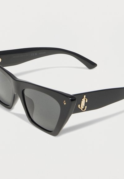 Μαύρα ορθογώνια γυαλιά ηλίου με σκούρους φακούς και λεπτομέρεια χρυσού λογότυπου στη σκελετό, απεικονιζόμενα σε λευκό φόντο.