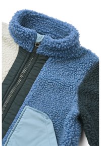 Ζακέτα από φλις με ψηλό γιακά, σε χρωματικό συνδυασμό μπλε και κρεμ, υφασμάτινη υφή, φερμουάρ μπροστά και αντίθετη τσέπη.