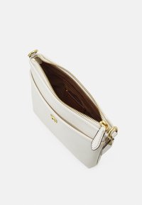Clutch bag in pelle bianca con chiusura a zip e hardware dorato. L'interno presenta una fodera marrone e una tasca per carte. Forma rettangolare compatta.