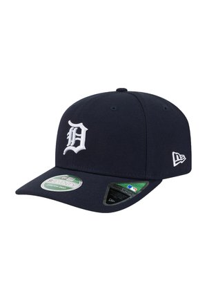 Dark blue baseball cap with white stitched "D" logo on front and a small white brand logo on the side, with two stickers on the curved brim.