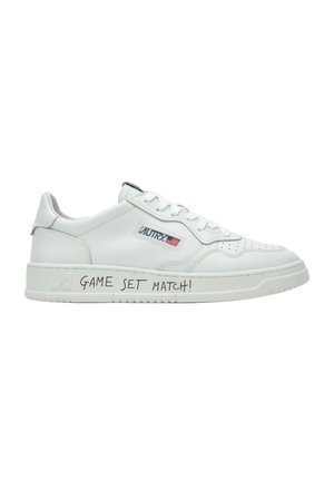 Sneaker bianca low-top con logo "AUTRY" e bandiera americana sul lato, e testo "GAME SET MATCH!" scritto sulla suola.
