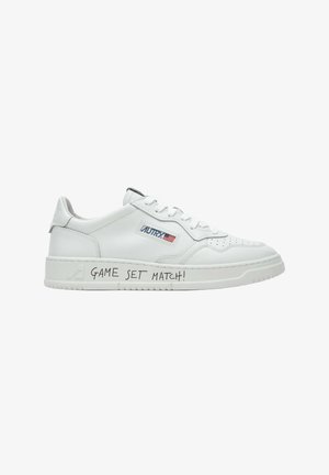 Sneaker bianca low-top con logo "AUTRY" e bandiera americana sul lato, e testo "GAME SET MATCH!" scritto sulla suola.