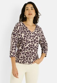 Jersey de leopardo de material suave, con escote en V, mangas de tres cuartos y una mezcla de tonos crema y púrpura.