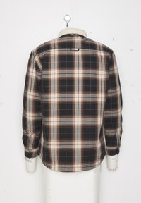 Flanellen shirt met een zwart, bruin en grijs geruit patroon, voorzien van een zachte witte kraag en knopenmanchetten, gepresenteerd op een mannequin.