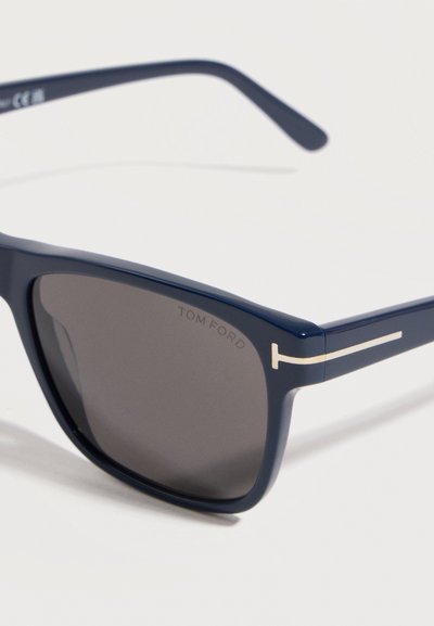 Dark blue rectangular sunglasses with black lenses, featuring a silver "T" detail on the temples and "Tom Ford" branding on the lens.