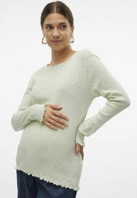 Šviesiai žalia ilgarankovė megzta palaidinė su akytų raštu, banguotomis rankovėmis ir apatine dalimi, šiek tiek prilipęs siluetas, švelni tekstūra.